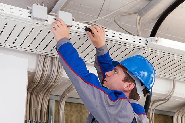 Technician installing UniFi access point on ceiling